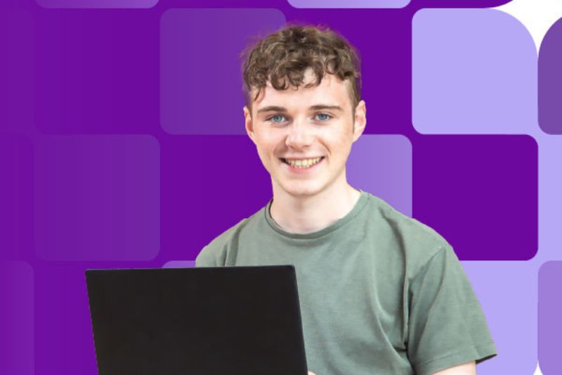 male student sitting with laptop smiling to camera